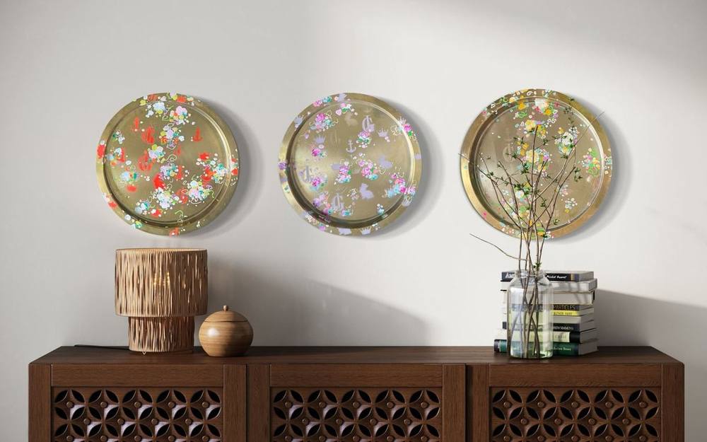 Drei runde Werke von Juliane Golbs mit Blüten auf goldenem Grund über einem Holzsideboard
